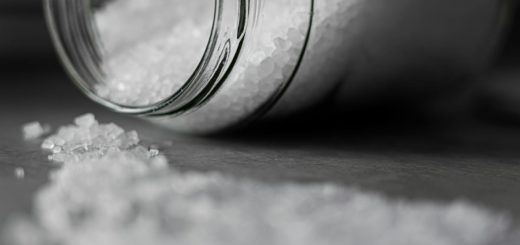 Detailed image of rock salt pouring out from a glass jar with a selective focus effect.